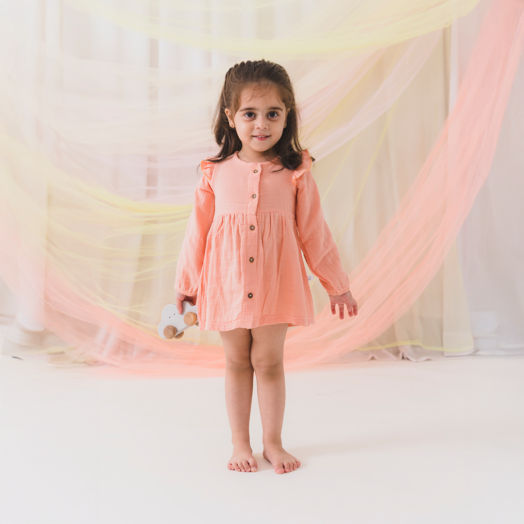 Young girl in a pink dress standing in front of a soft, blurred background