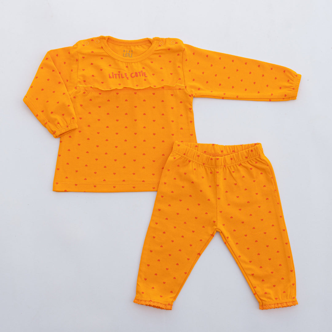 A set of children's clothing, with orange top and leggings, adorned with heart patterns and lace trim.