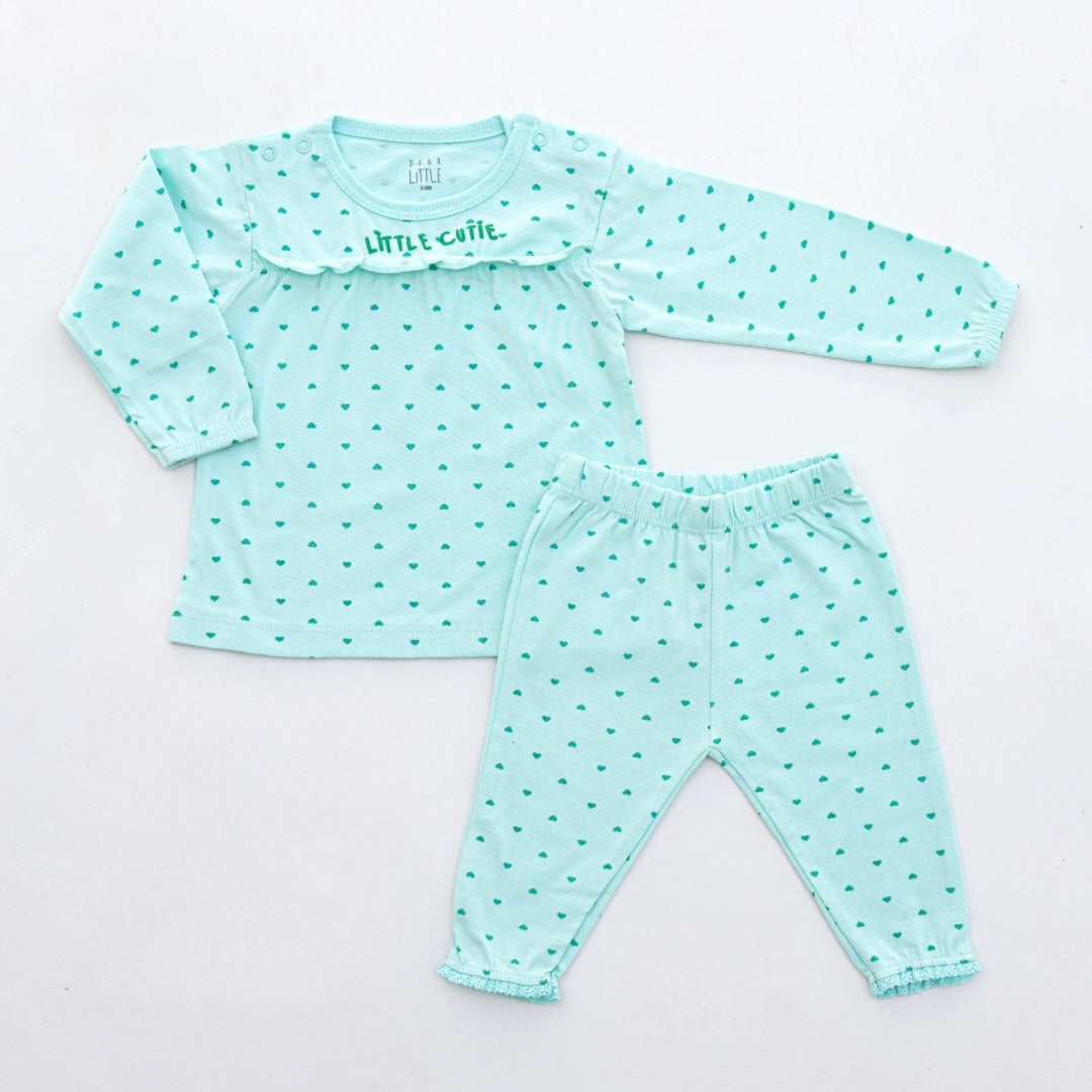 A set of children's clothing, with a long-sleeve top and leggings, in green with a pattern of hearts and dots, and lace trim at the edges.