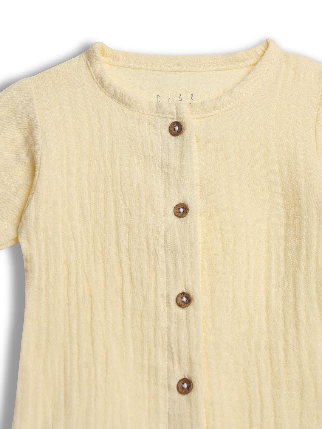 Close-up of a yellow textured garment with brown buttons 