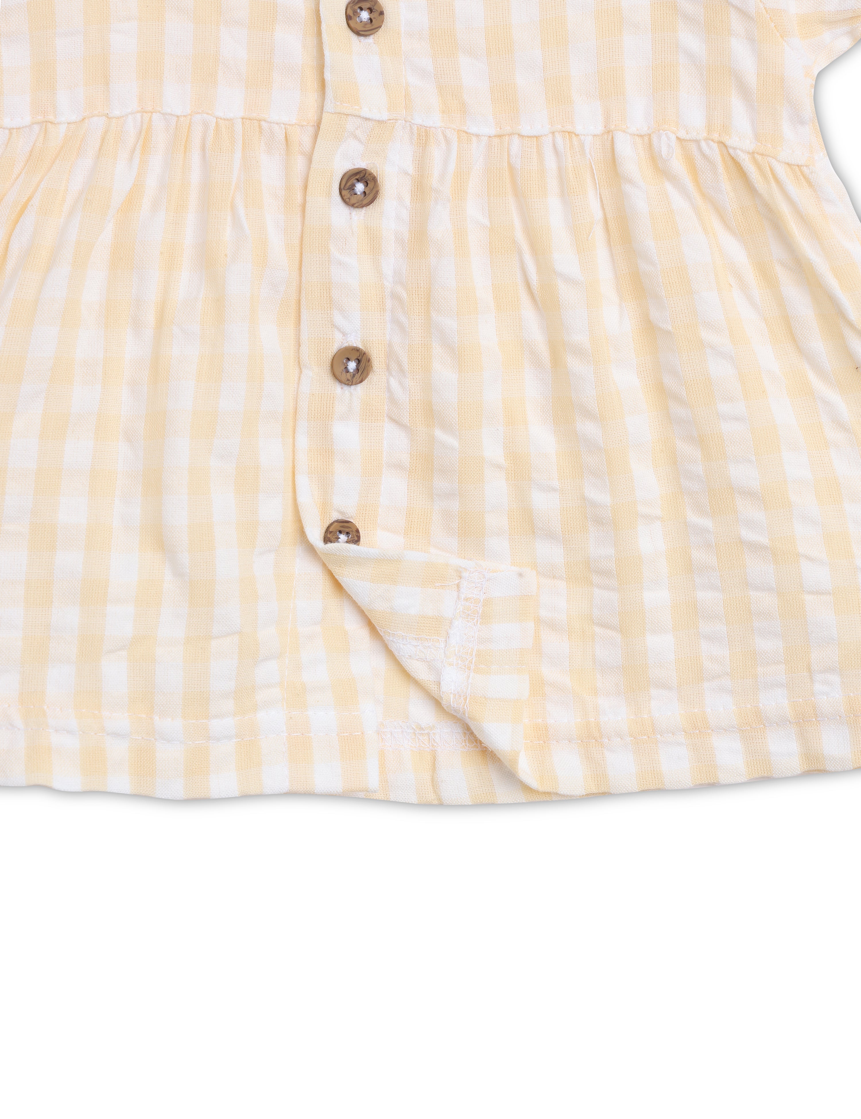 Close-up of a yellow and white striped dress with brown buttons on a white background