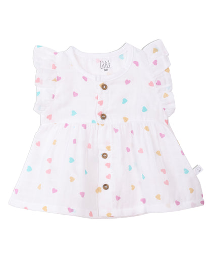 A white muslin frock with multicolor heart prints, ruffle sleeves, and wooden buttons designed for babies.