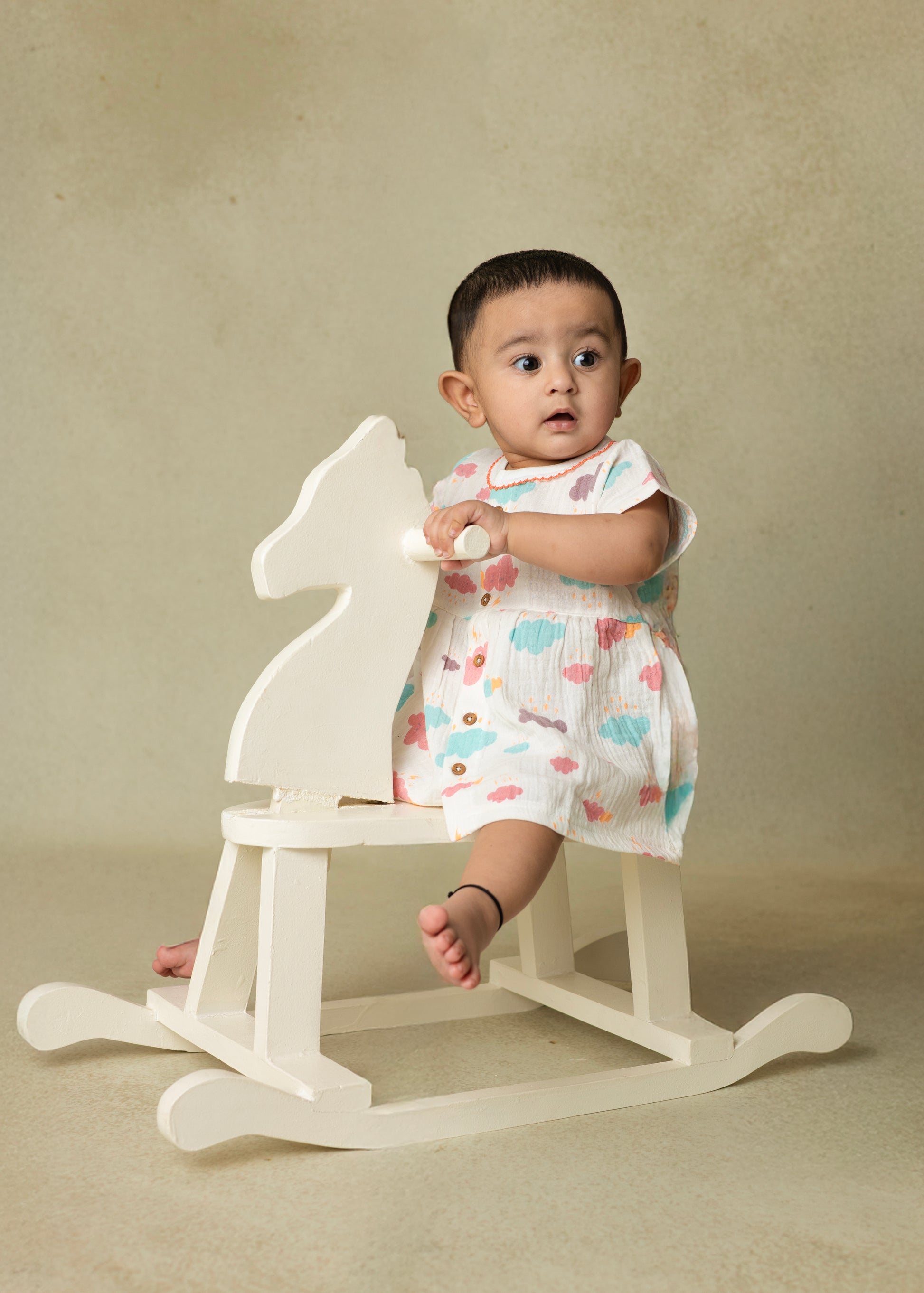 A baby wearing a short-sleeved purple and blue crinkled muslin frock