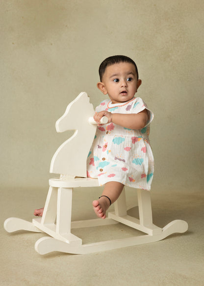 A baby wearing a short-sleeved purple and blue crinkled muslin frock